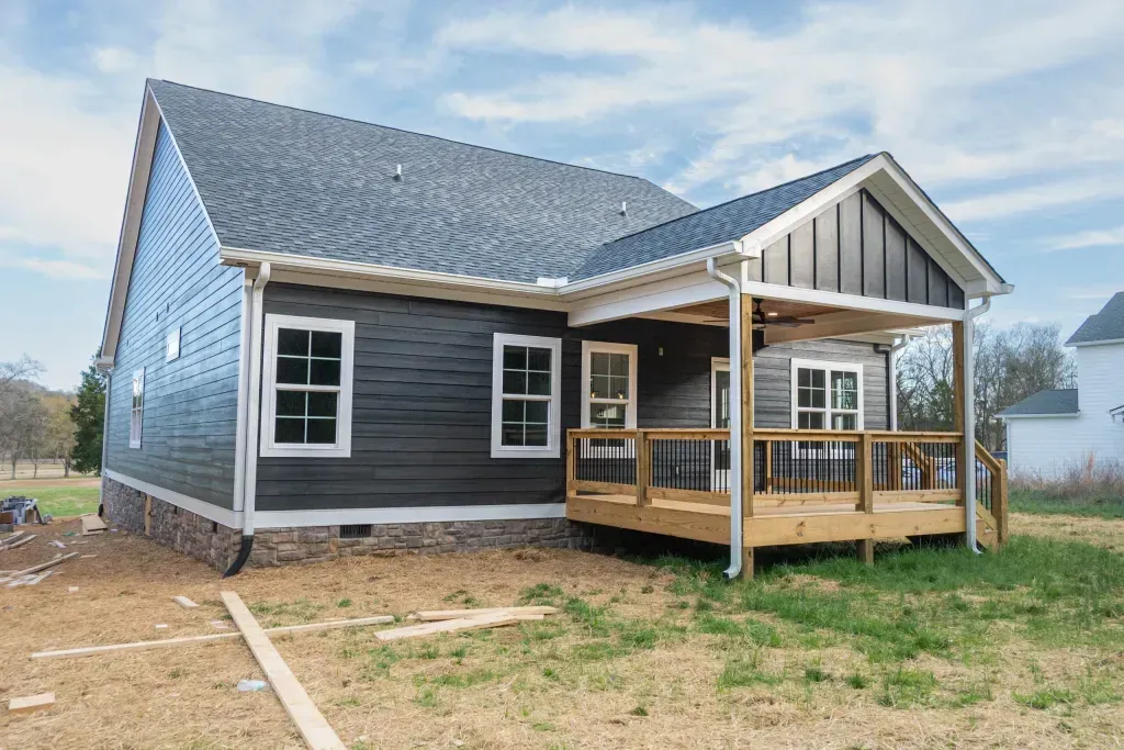 The back of a house with a porch and a blue roof is being built.