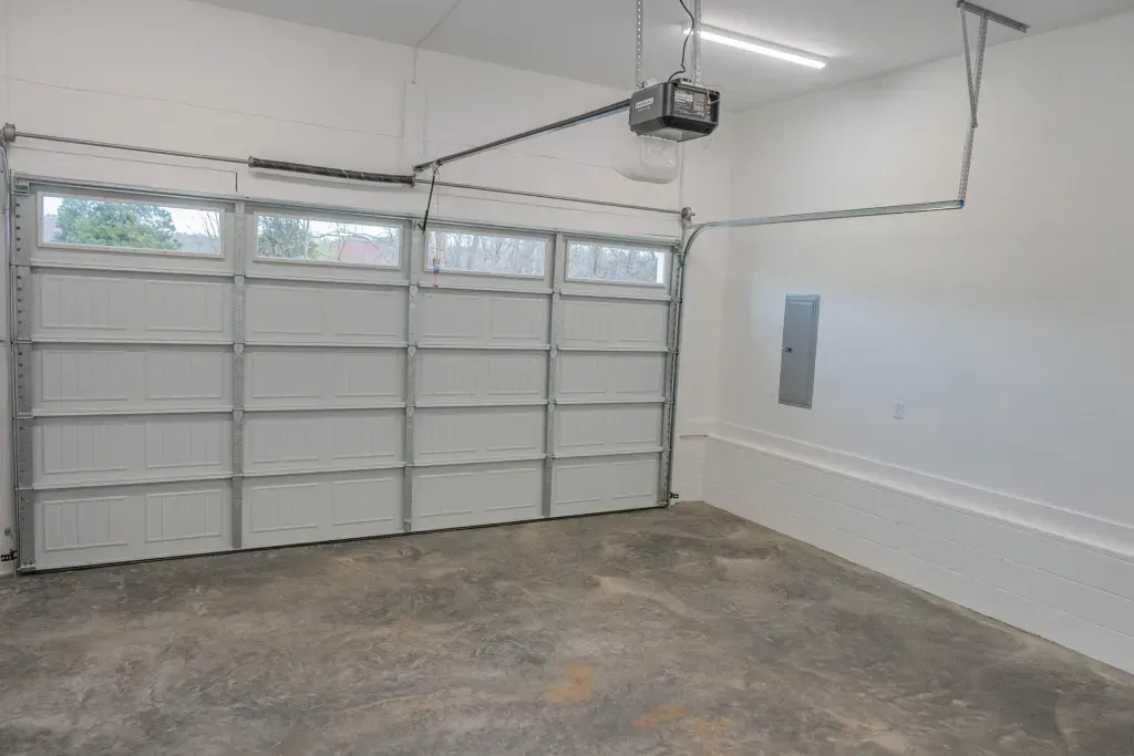 An empty garage with a garage door open and a garage door opener.