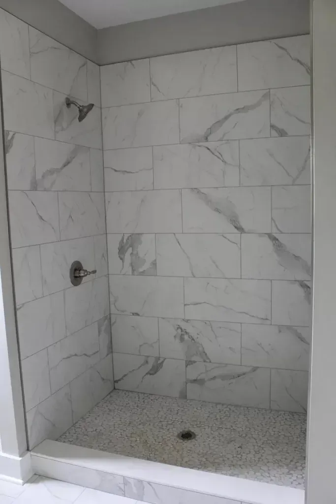 A shower stall with marble tiles and a shower head.