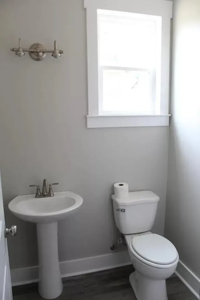 A bathroom with a toilet , sink and window.