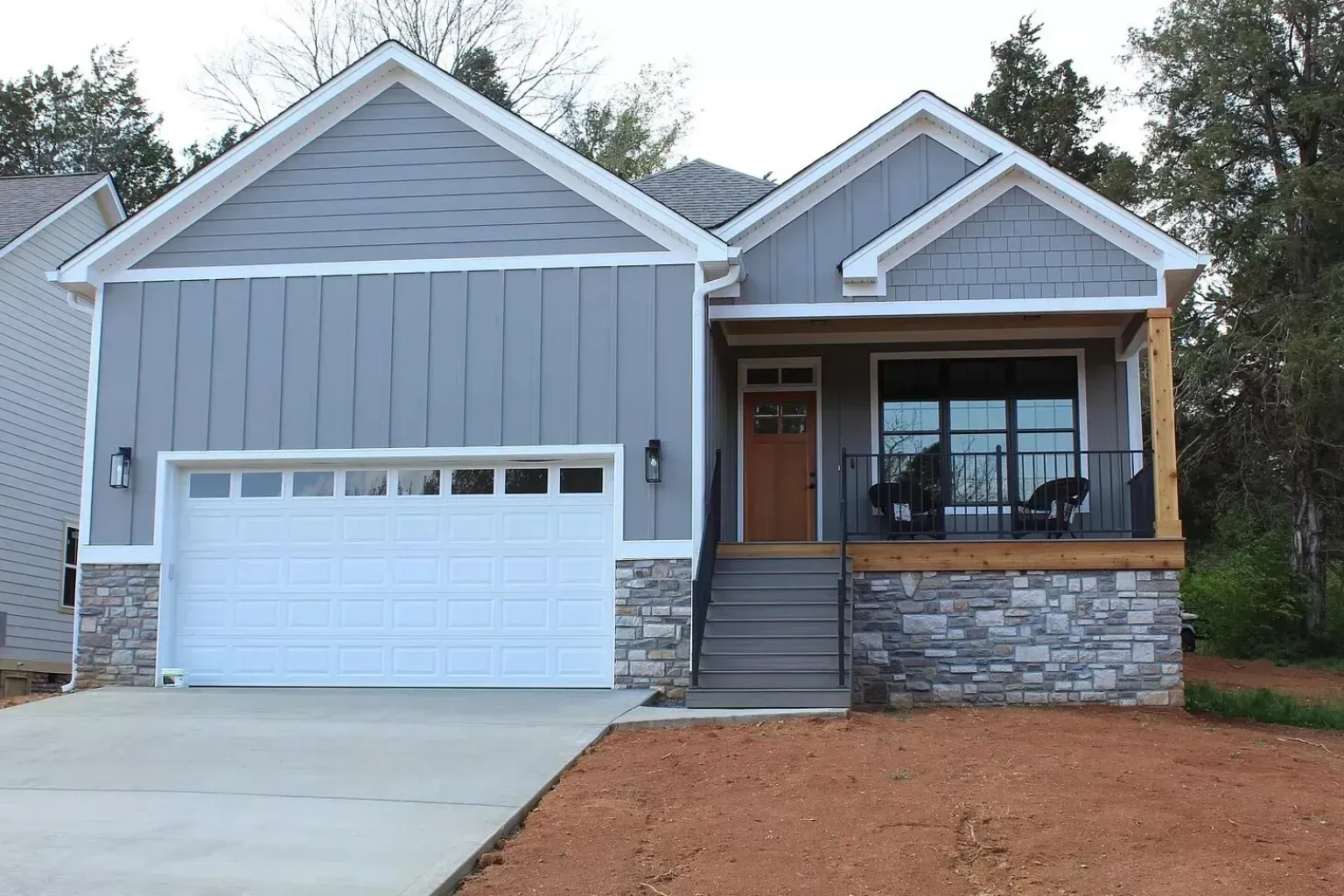 A gray house with a white garage door and a porch.