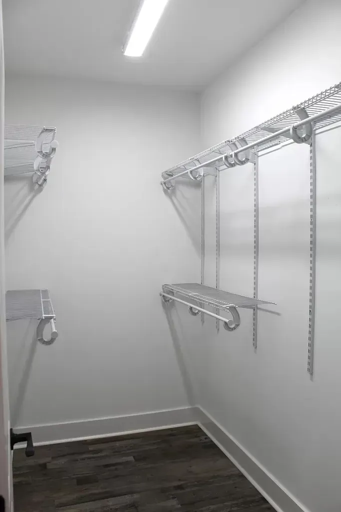 A walk in closet with lots of shelves and hooks.