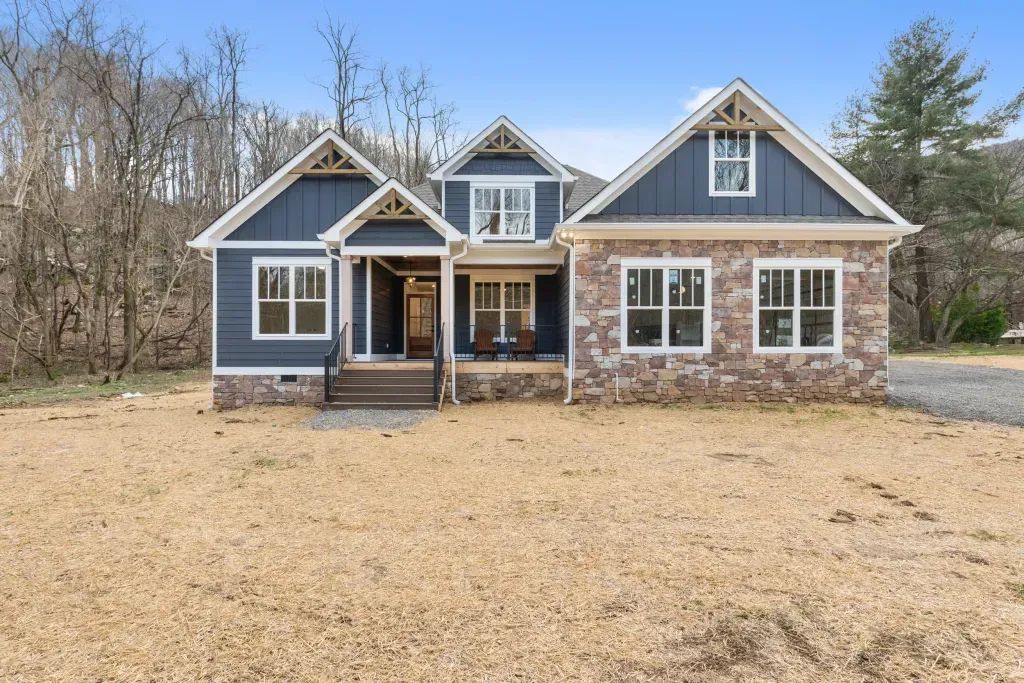 House exterior with blue siding, stone accents, and triangular roof details on a sunny day.