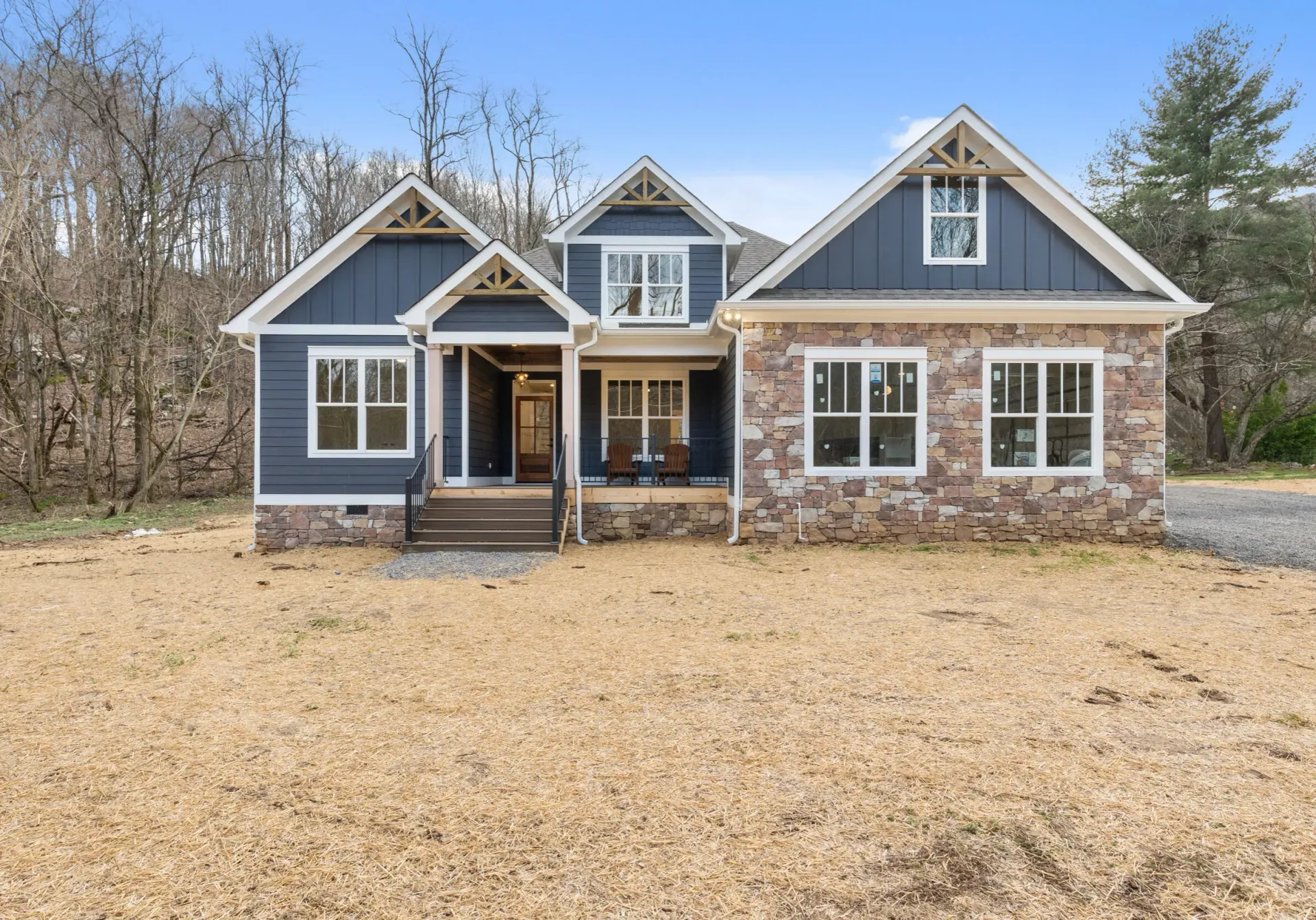 A large house with a lot of windows is sitting on top of a dirt field.
