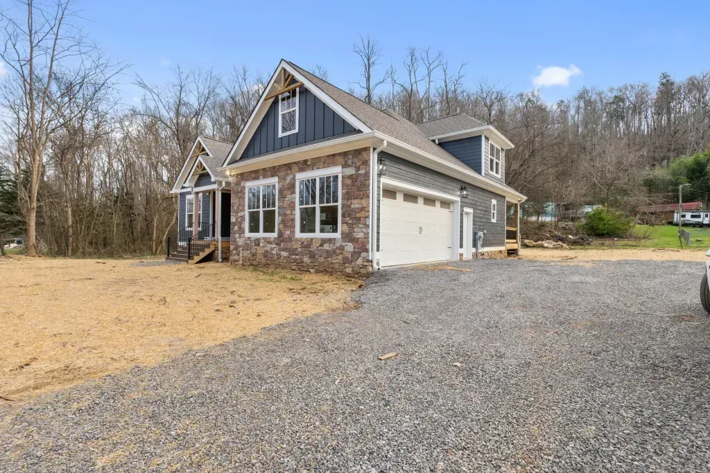 A house with a garage and a car parked in front of it.