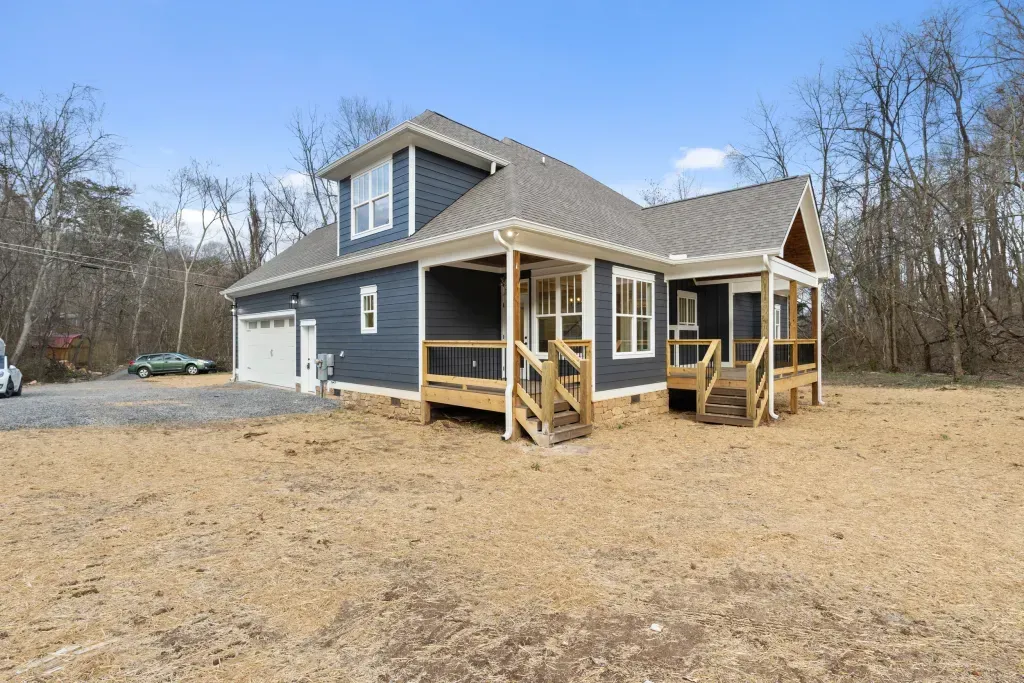A large house is sitting in the middle of a dirt field.