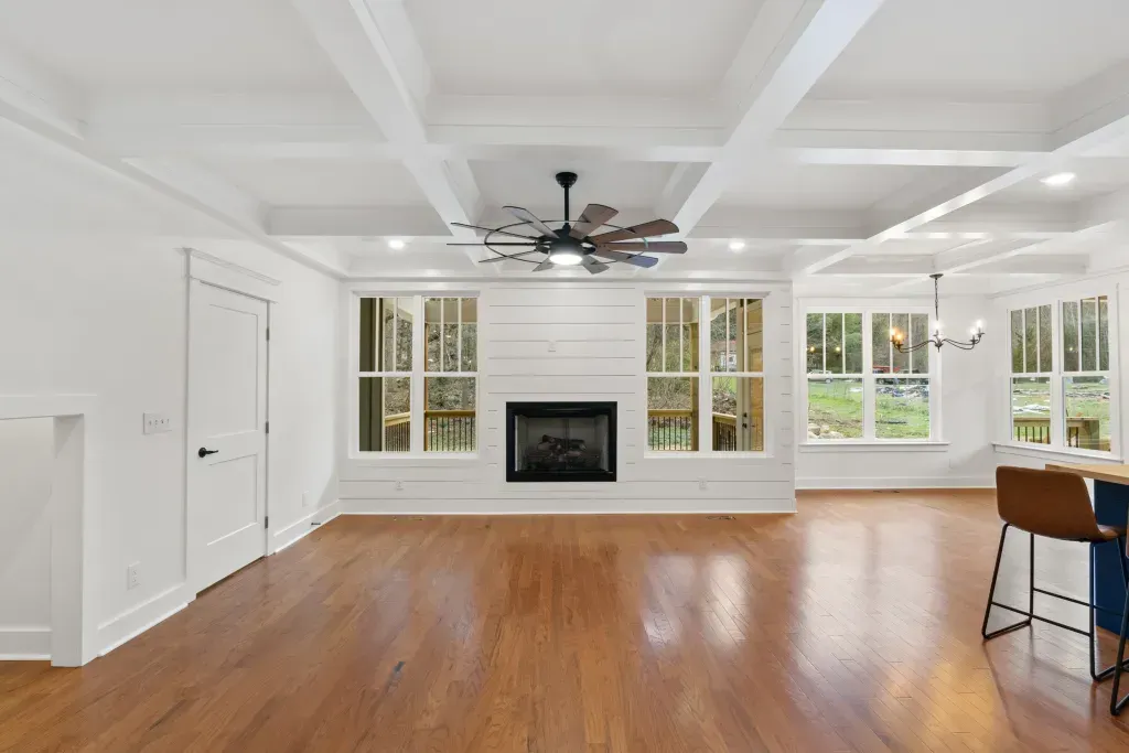 An empty living room with hardwood floors and a fireplace.