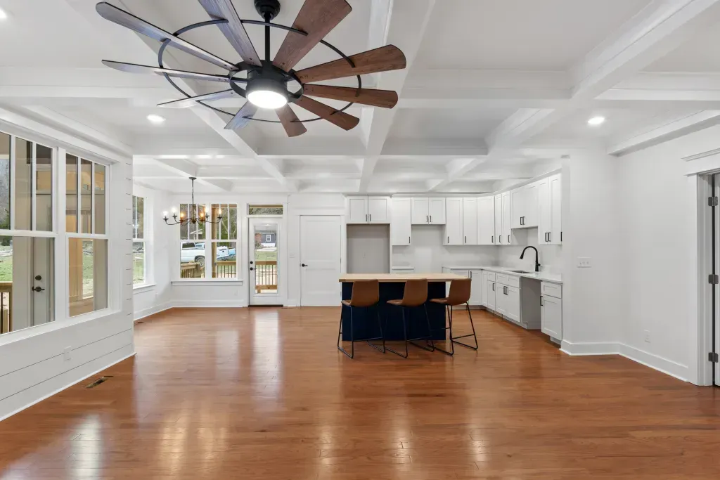 A large empty room with hardwood floors and a ceiling fan.