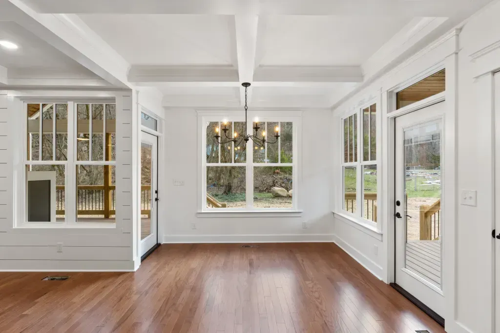 An empty living room with hardwood floors and white walls.