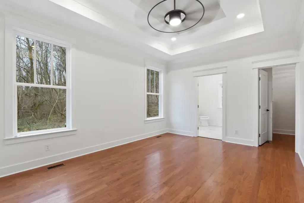 An empty room with hardwood floors and a ceiling fan.