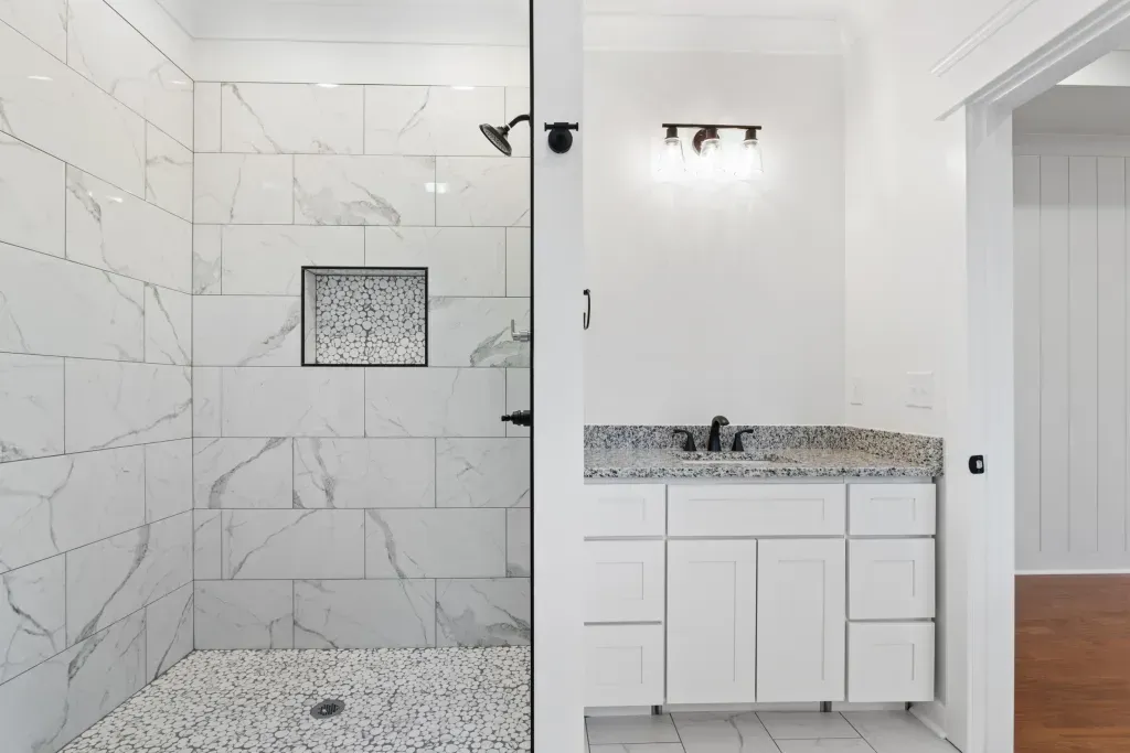 A bathroom with a walk in shower and a vanity.