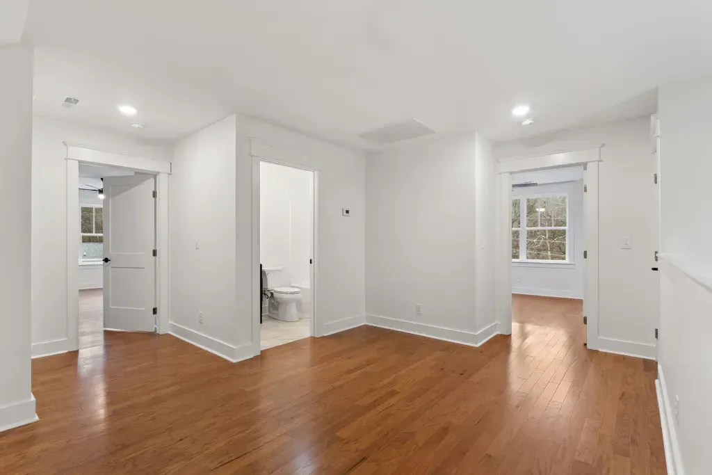 An empty living room with hardwood floors and white walls.