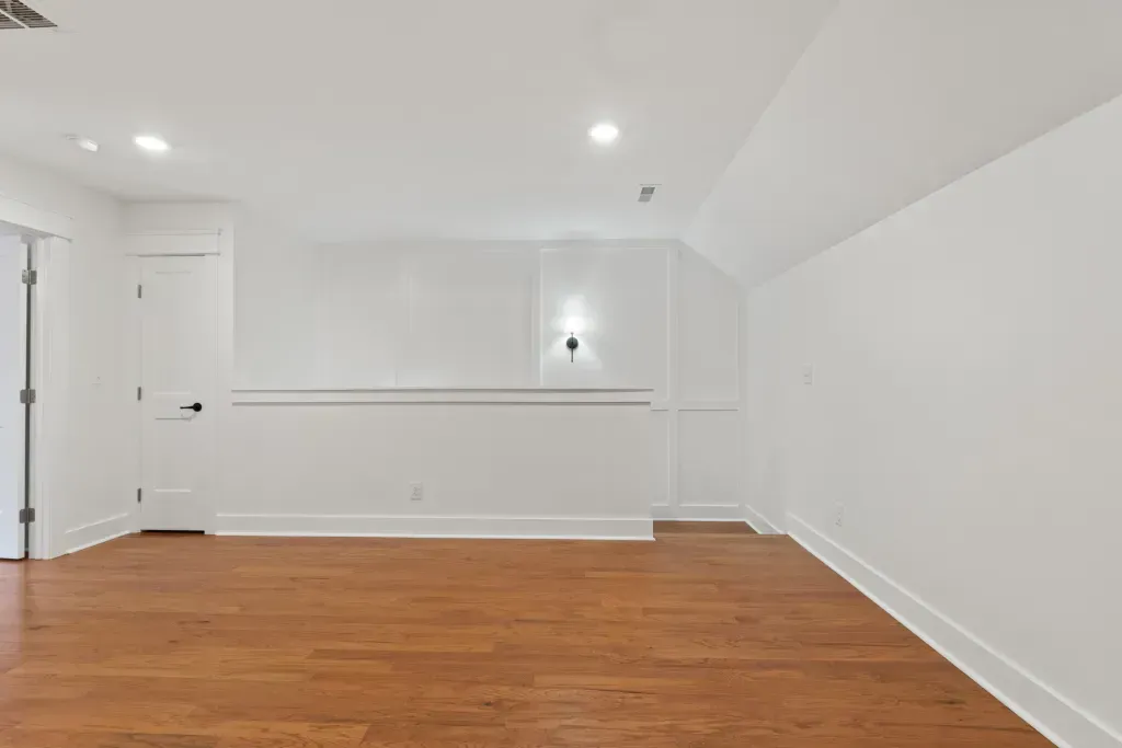 An empty room with hardwood floors and white walls.