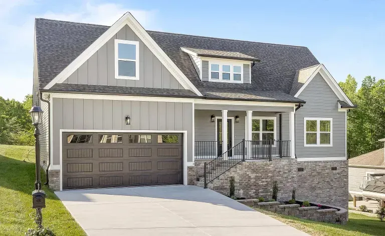 A large gray house with a brown garage door and a driveway.