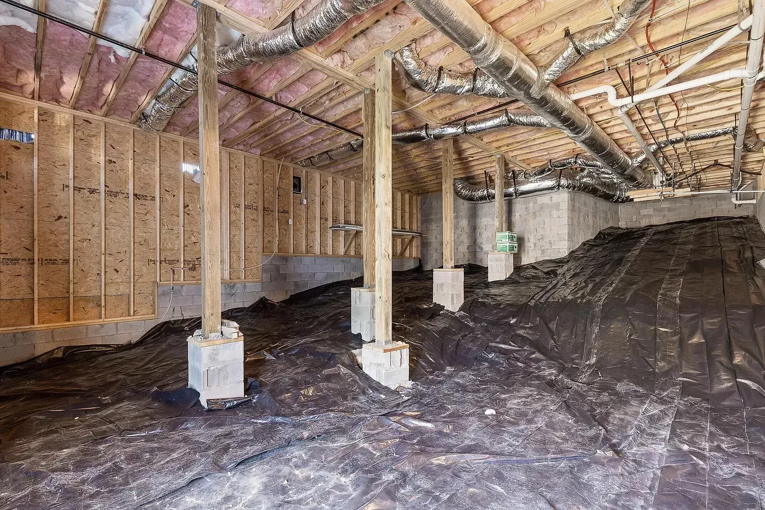 A basement under construction with a lot of pipes coming out of the ceiling.