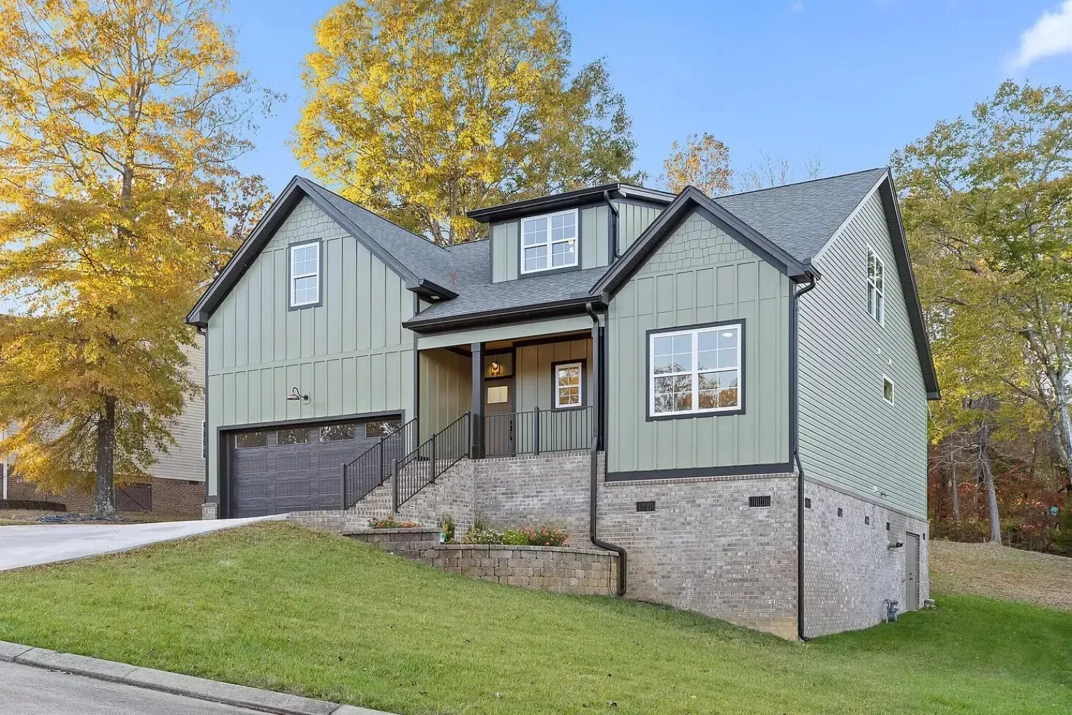 A house with a green siding and a black roof is for sale.