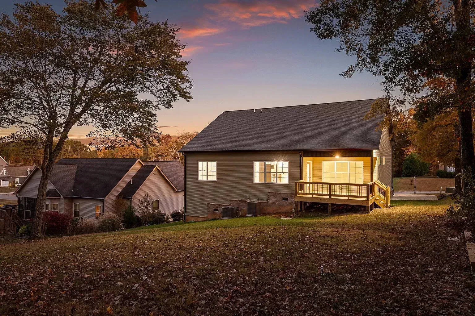 A house with a large deck is lit up at night.