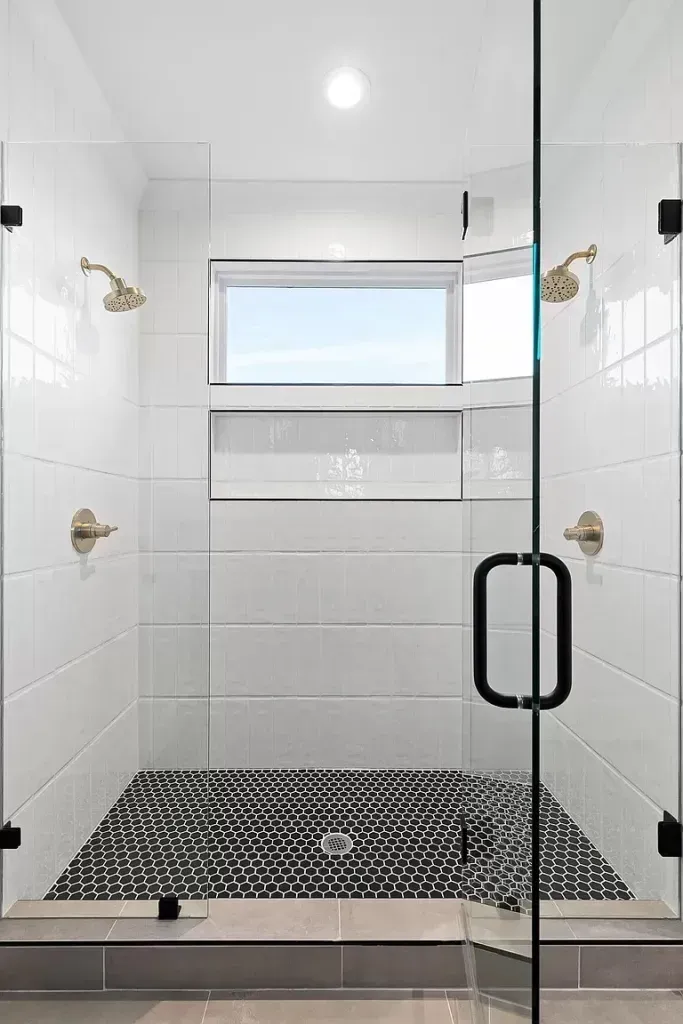 A bathroom with a walk in shower and a window.