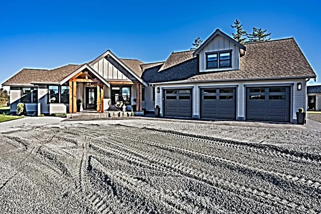 A large house with a lot of garage doors is sitting on top of a dirt field.