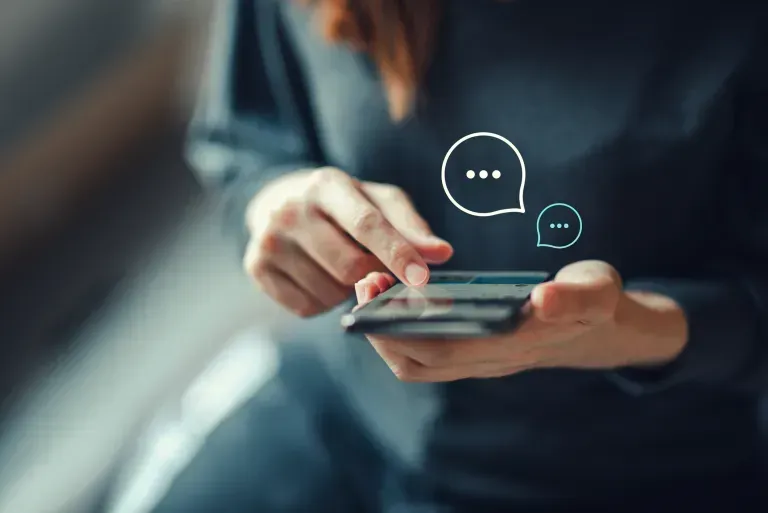 A woman is using a smart phone with speech bubbles coming out of it.
