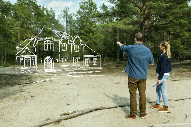 A man and a woman are standing in front of a drawing of a house.