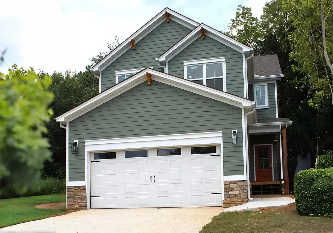 A large green house with a white garage door