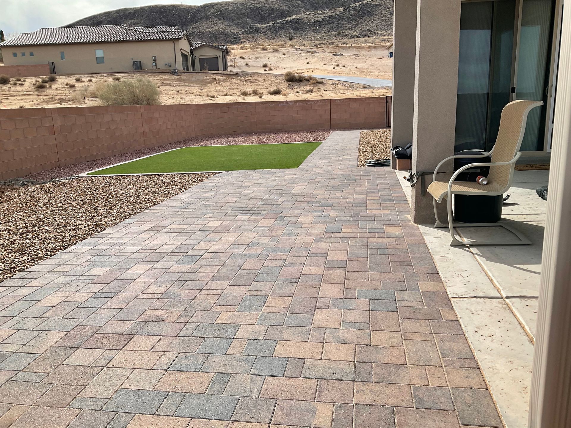 A patio with a chair on it and a house in the background