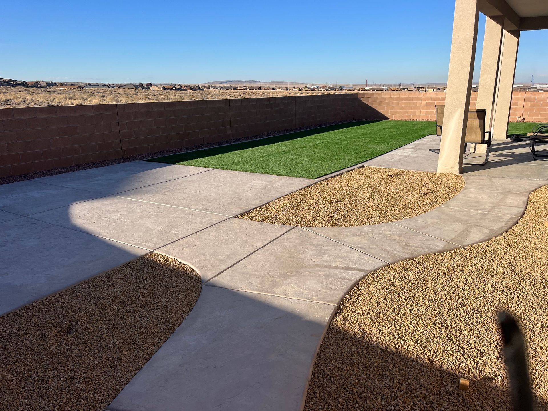 A patio with a bench and a brick wall in the background