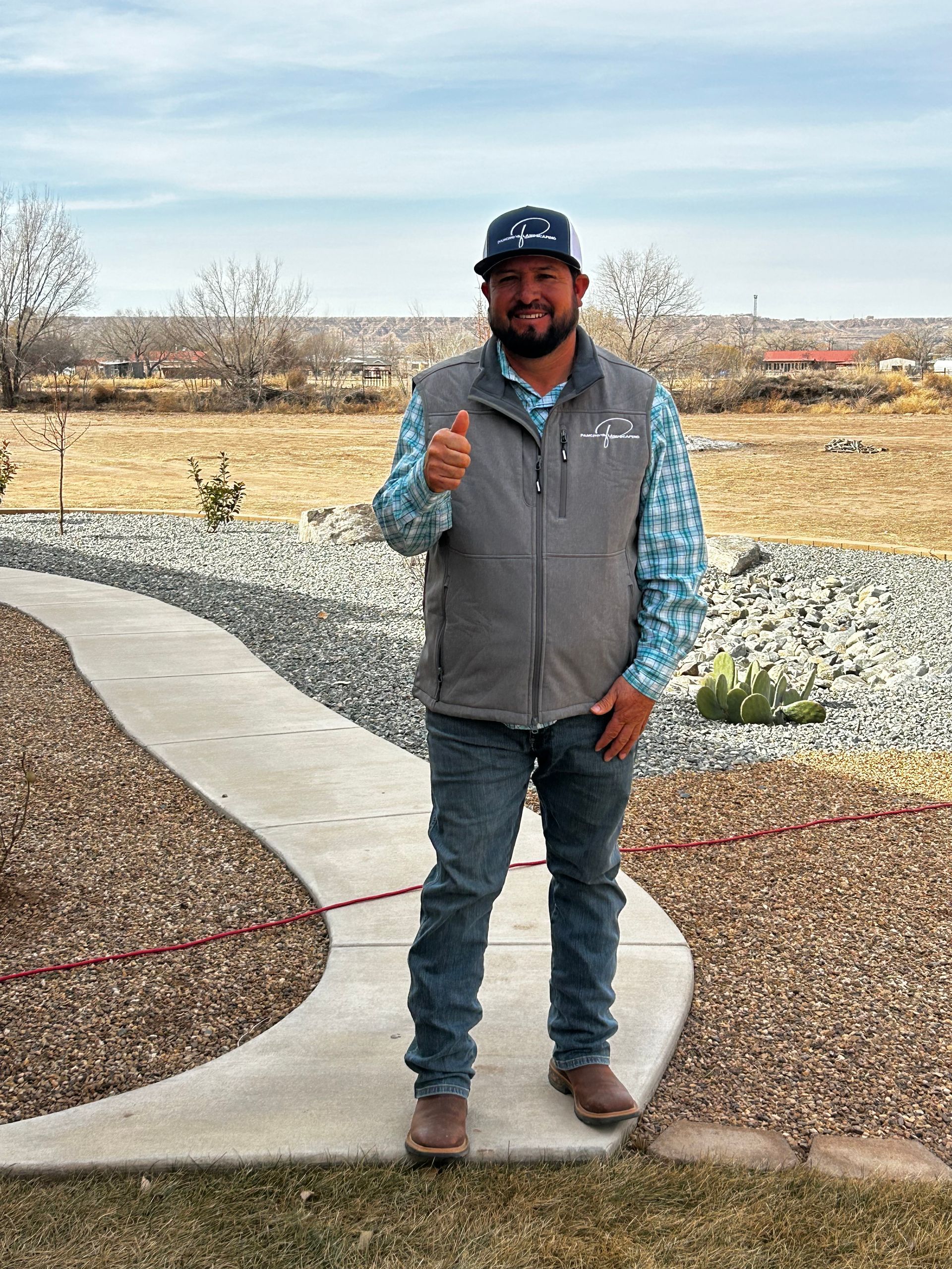 A man is standing on a sidewalk giving a thumbs up.