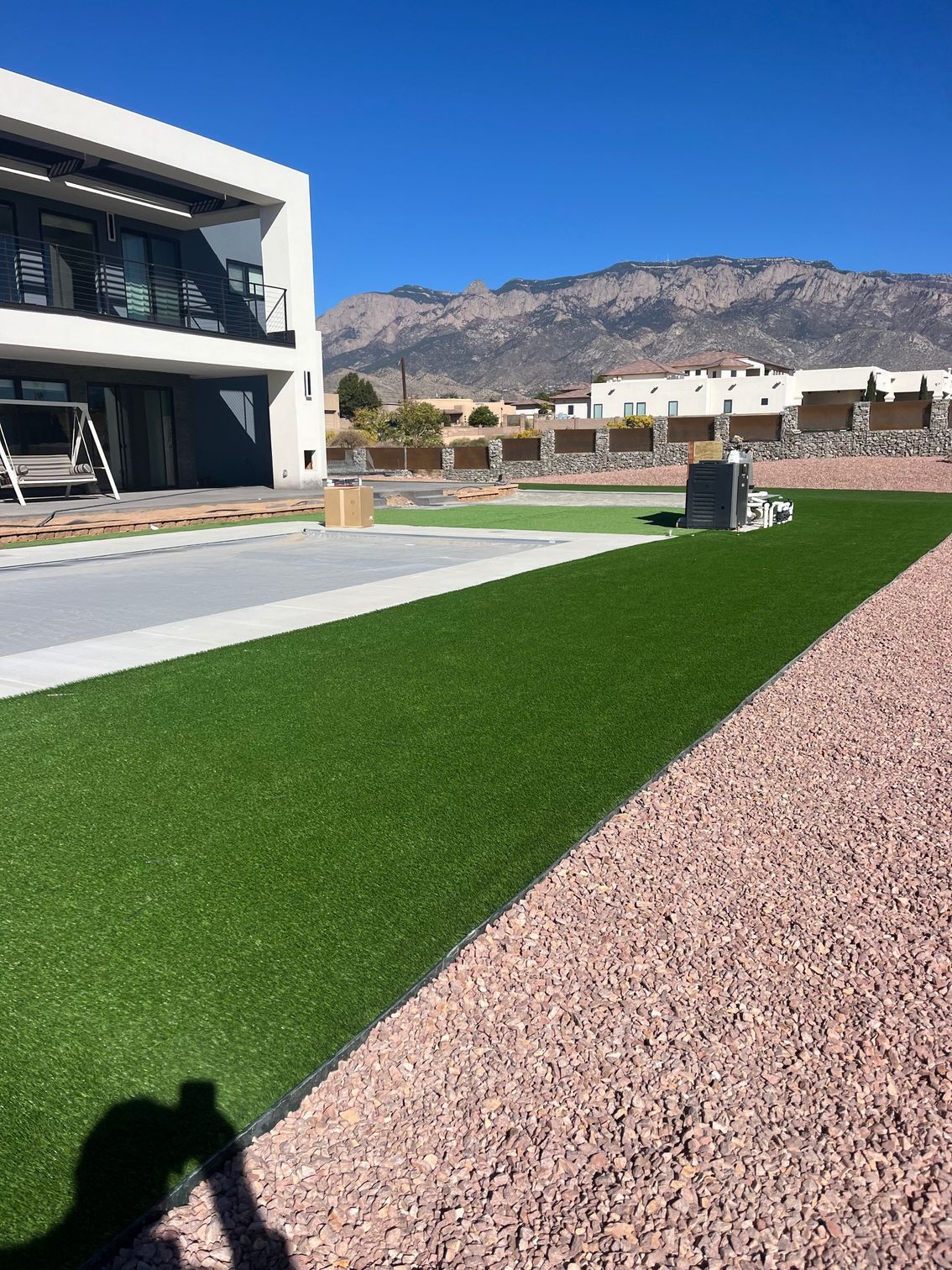 A person is taking a picture of a house with mountains in the background.