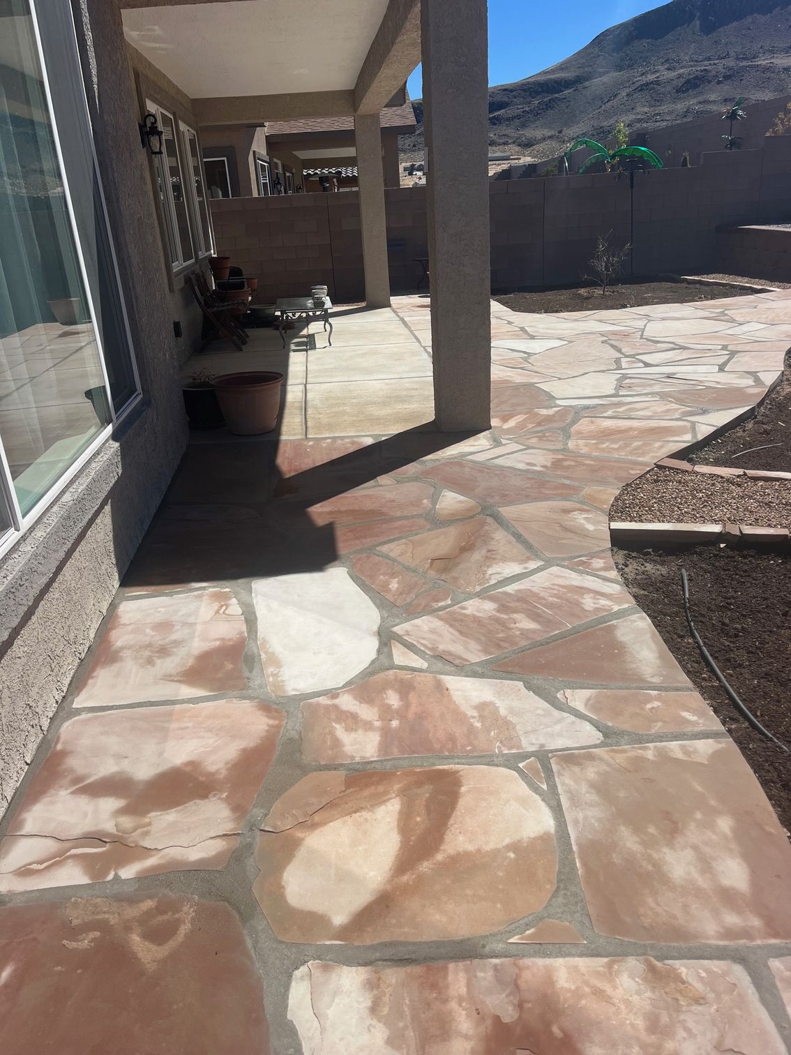 A stone walkway leading to a patio with a mountain in the background.