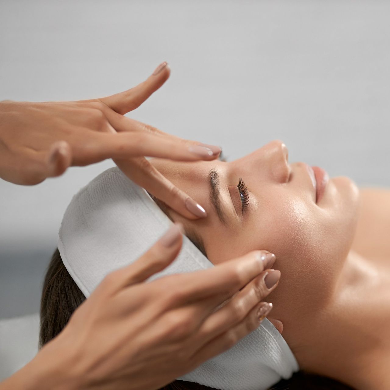 A woman with a bandage on her head is getting a facial massage