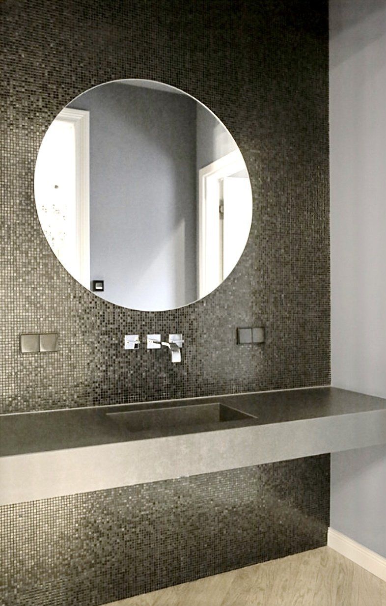 Ein Badezimmer mit Waschbecken und rundem Spiegel