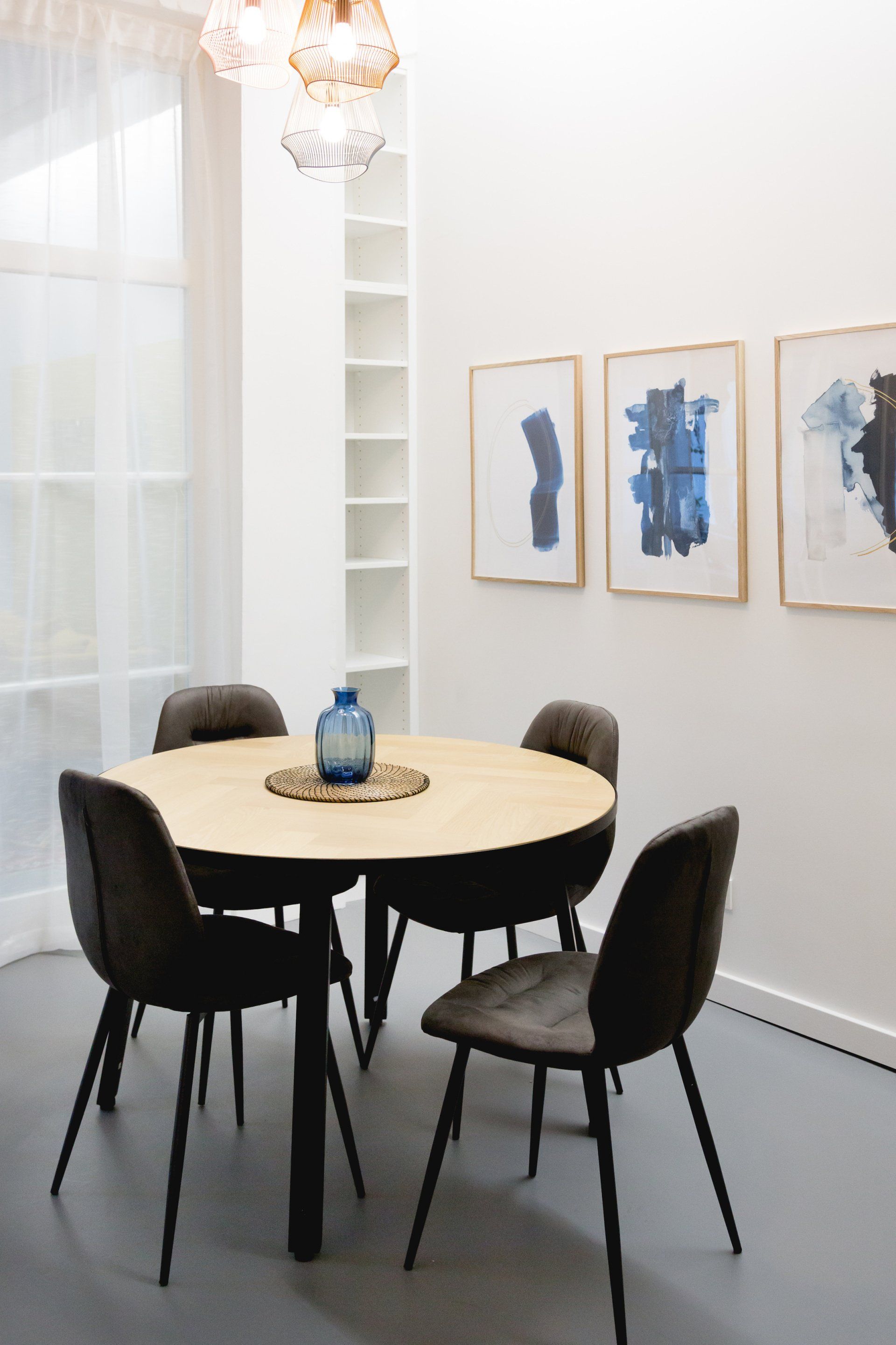 Ein Esszimmer mit einem runden Tisch und Stühlen und Gemälden an den Wänden.