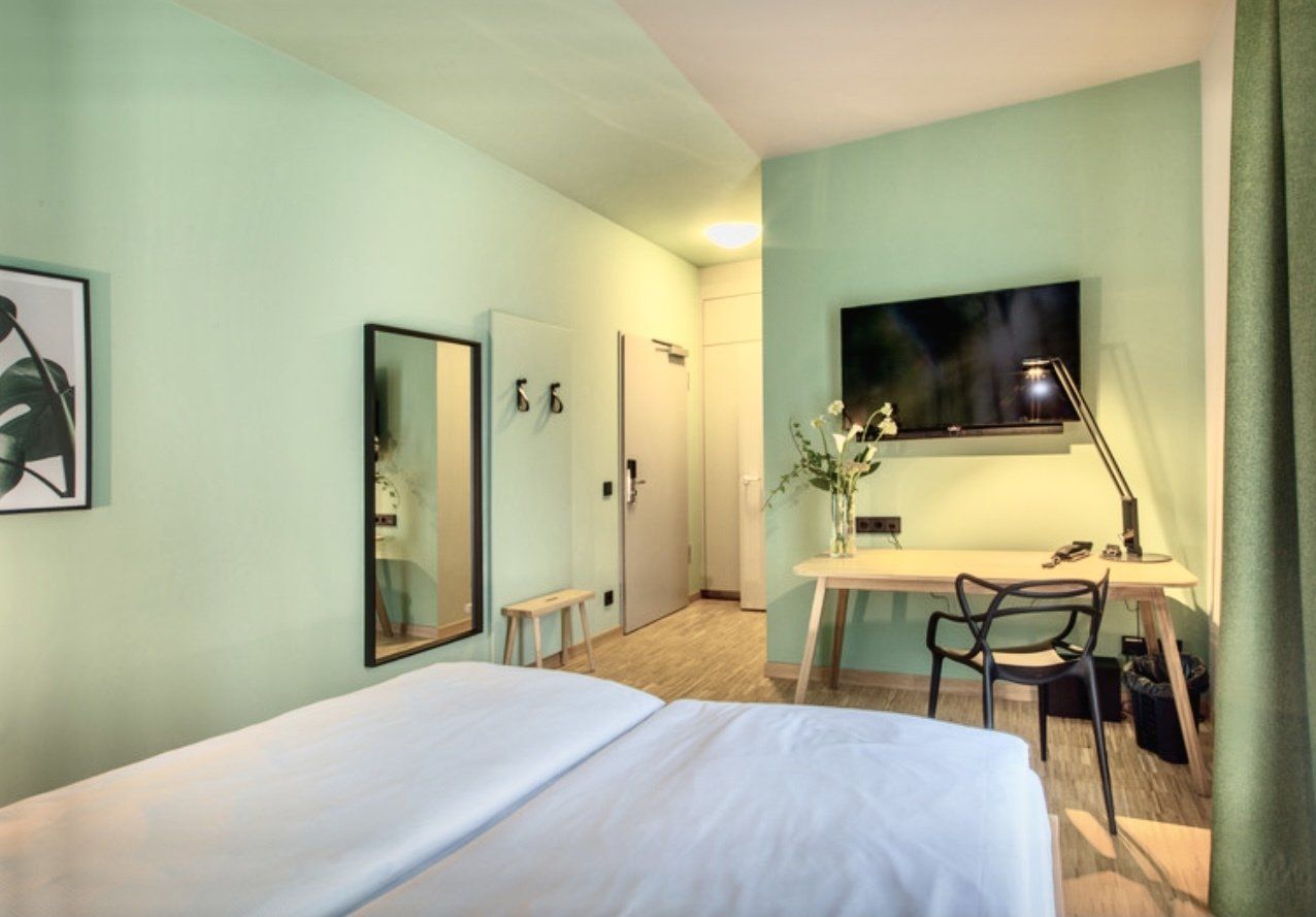 Ein Hotelzimmer mit Bett, Schreibtisch, Stuhl und Fernseher.