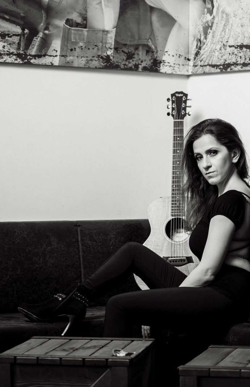 Eine Frau sitzt auf einer Couch und hält eine Gitarre