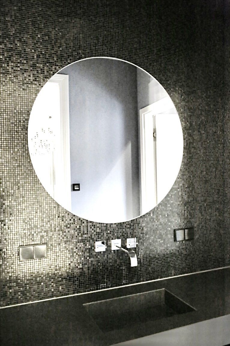 Ein Badezimmer mit einem runden Spiegel über einem Waschbecken