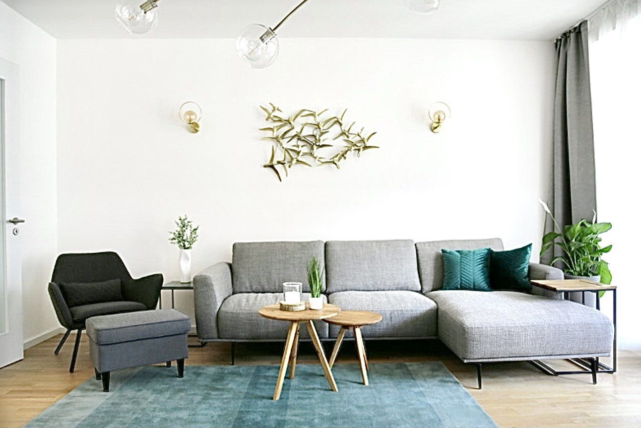 Ein Wohnzimmer mit Couch, Sessel, Tisch und Teppich.