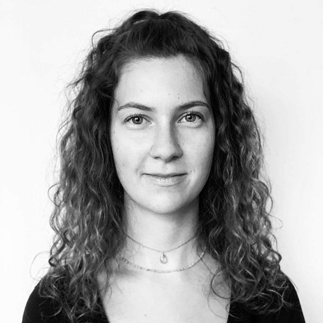 Ein Schwarzweißfoto einer Frau mit lockigem Haar und einer Halskette.