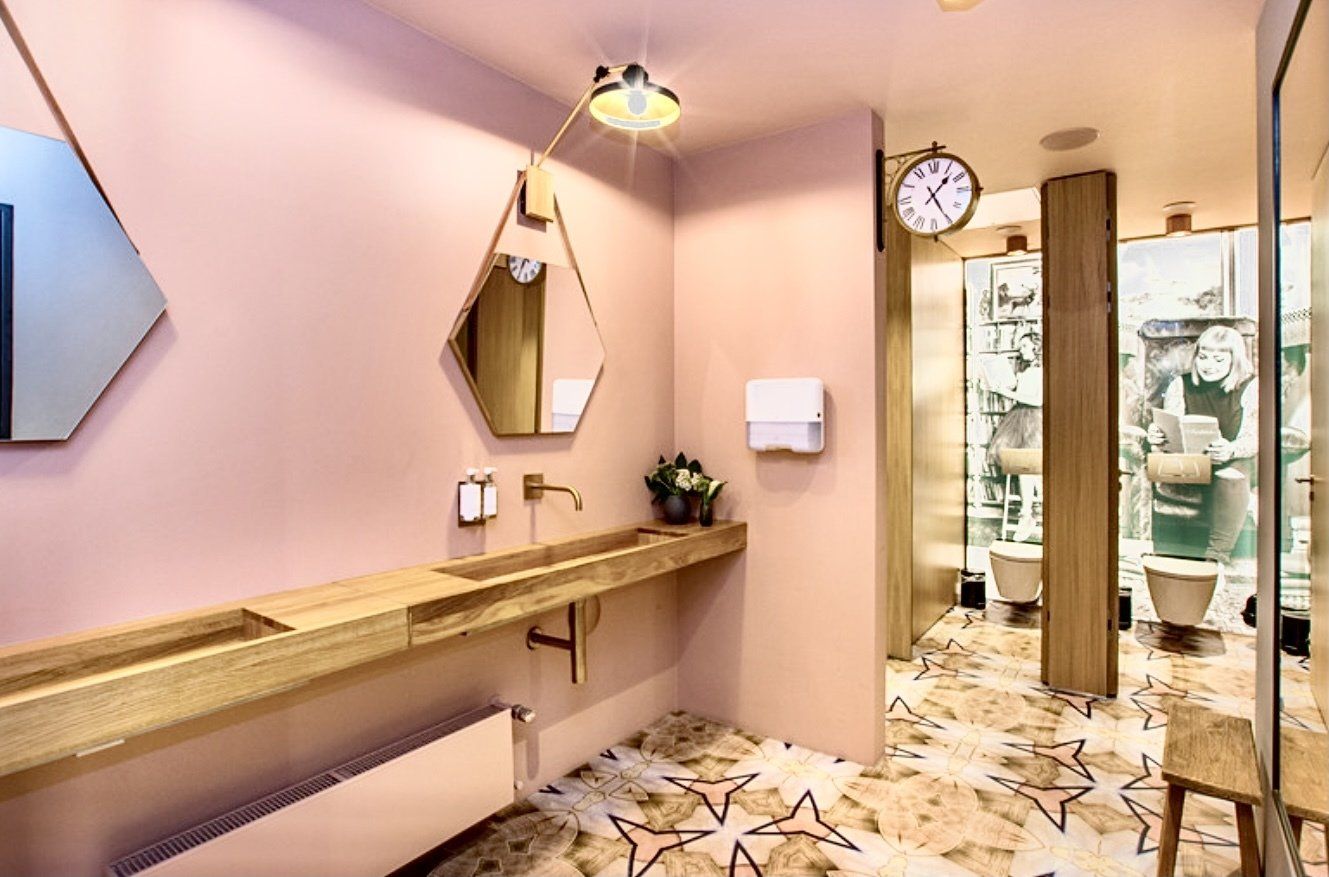 Ein Badezimmer mit Waschbecken, Spiegel und Uhr an der Wand.