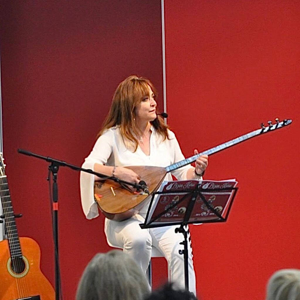 Eine Frau spielt Gitarre und singt in ein Mikrofon