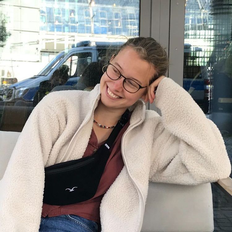 Eine Frau mit Brille und weißer Jacke lächelt