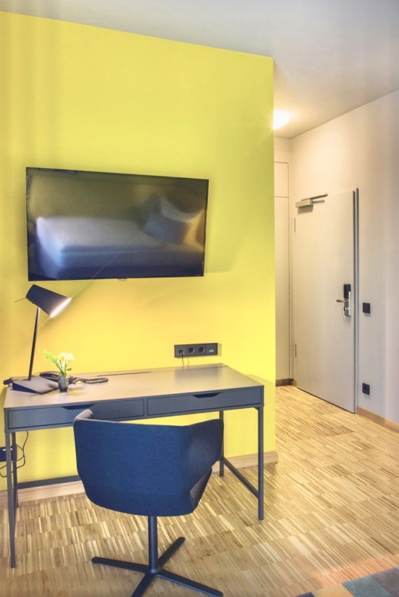 Ein Zimmer mit einer gelben Wand und einem Schreibtisch und Stuhl