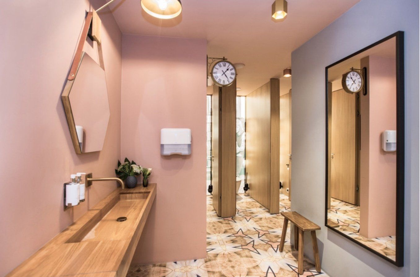 Ein Badezimmer mit Waschbecken, Spiegel und Uhr an der Wand.