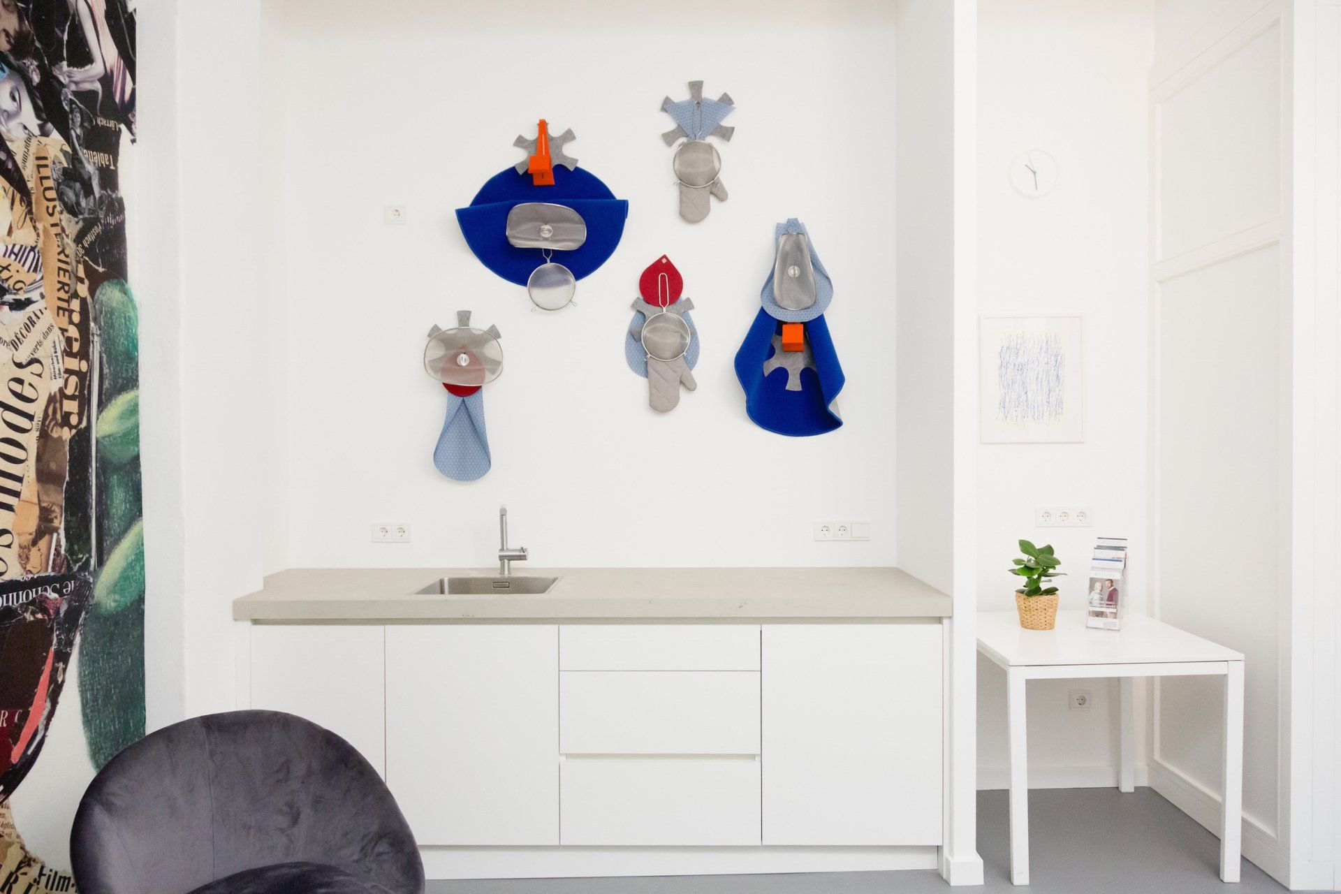 Eine Küche mit Spüle, Stuhl, Tisch und Bildern an der Wand.