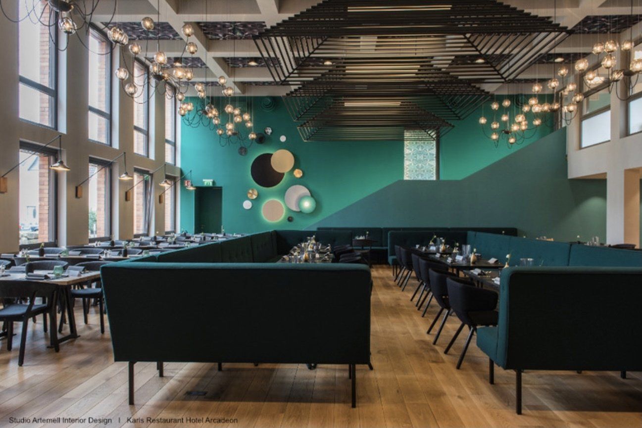 Ein Restaurant mit Tischen und Stühlen und einer grünen Wand.