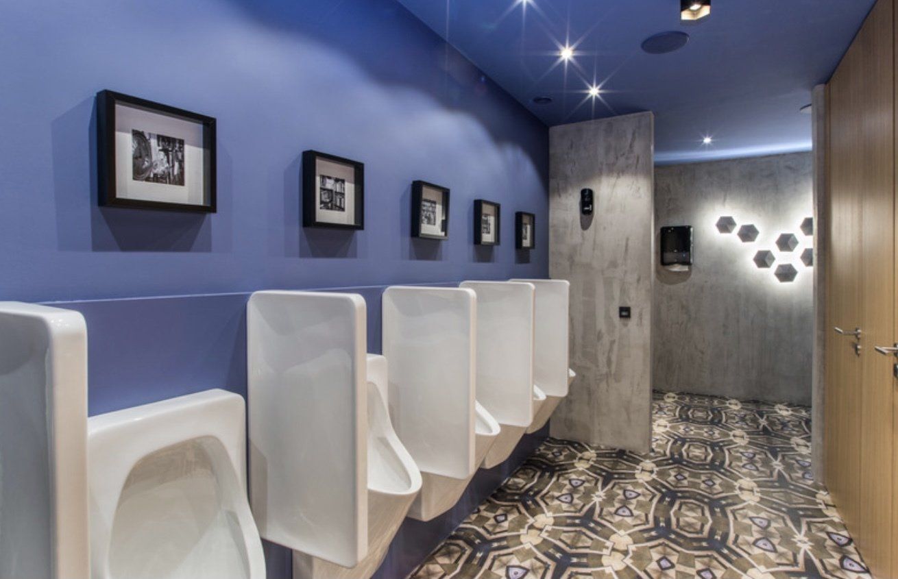 Ein Badezimmer mit violetten Wänden und weißen Urinalen.