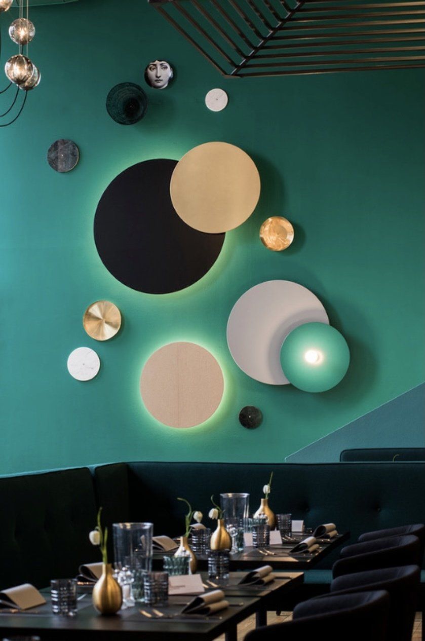 Ein Restaurant mit Tischen und Stühlen und einer grünen Wand mit Kreisen darauf