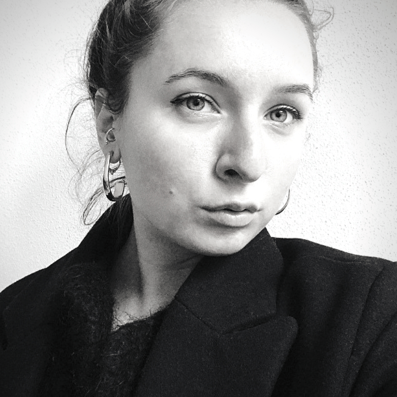 Ein Schwarzweißfoto einer Frau, die eine Jacke und Ohrringe trägt.