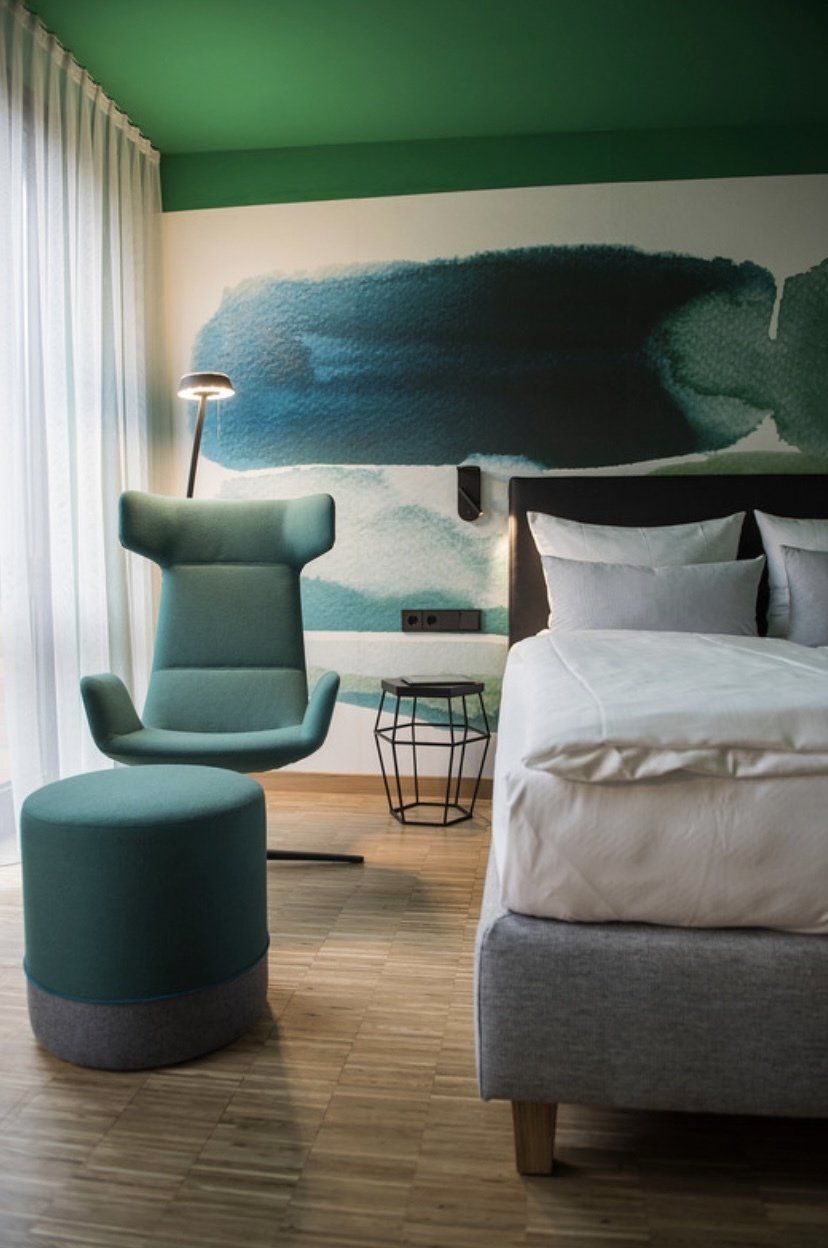 Ein Hotelzimmer mit Bett, Sessel und Ottomane.